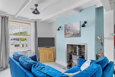 a blue living room with a blue couch and a tv at Finest Retreats - Farleigh Cottage in Looe