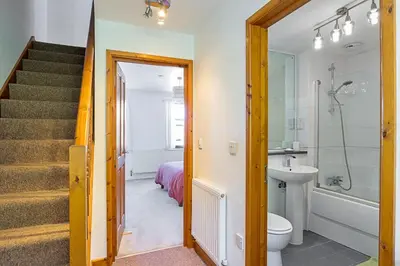 a bathroom with a sink and a toilet and a staircase at Finest Retreats - Williams Court in Falmouth