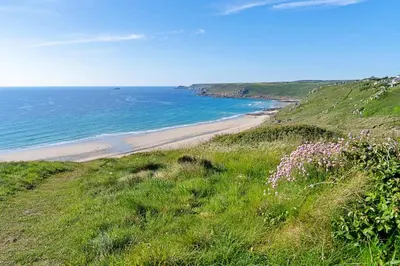 a view of a beach from a hill with flowers at Finest Retreats - Williams Court in Falmouth