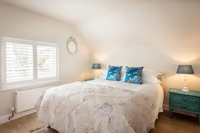 a bedroom with a bed with blue pillows and a window at Compass Rose in Port Isaac