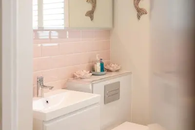 a bathroom with a sink and a toilet with pink tiles at Compass Rose in Port Isaac
