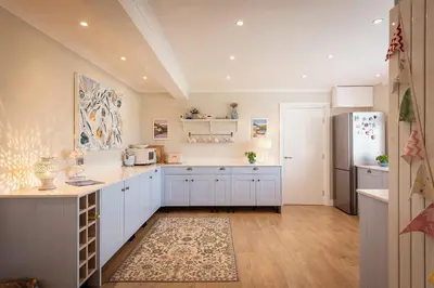 a kitchen with white cabinets and a refrigerator at Compass Rose in Port Isaac