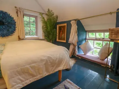 a bedroom with a large bed and two windows at Mermaid Cottage in Helston