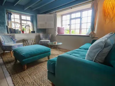a living room with a blue couch and chairs at Mermaid Cottage in Helston