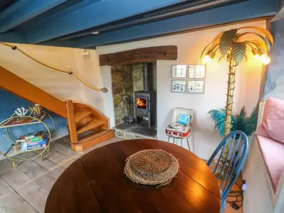 a dining room with a table and a wood stove at Mermaid Cottage in Helston