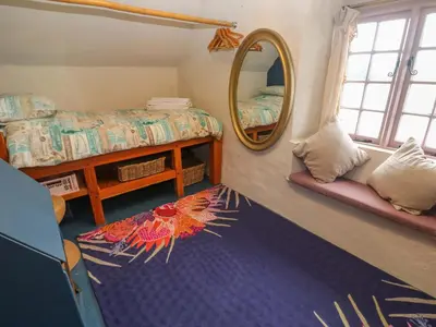 a bedroom with a mirror and a bed and a rug at Mermaid Cottage in Helston