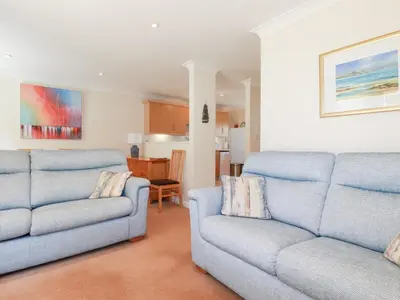 a living room with two blue couches and a kitchen at Trouts Reach in Falmouth