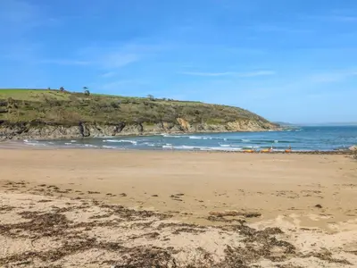 a beach with the ocean and a hill in the background at Trouts Reach in Falmouth