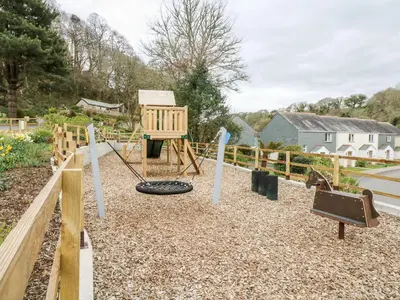 a playground in a garden with a swing at Trouts Reach in Falmouth