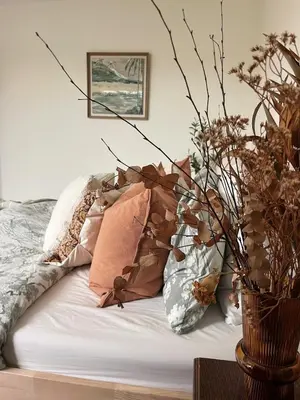 a bed with pillows and a vase with flowers at SeaNest, Aggie Home by the sea in St. Agnes