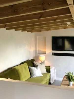 a living room with a green couch and a flat screen tv at SeaNest, Aggie Home by the sea in St. Agnes