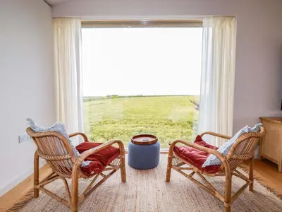 a living room with two chairs and a large window at 8 Karn Havos in Wadebridge
