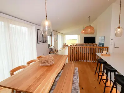 a dining room and living room with a wooden table at 8 Karn Havos in Wadebridge
