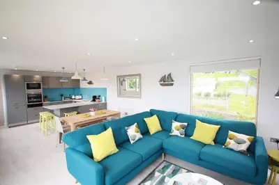 a living room with a blue couch and a kitchen at House 18 in Looe