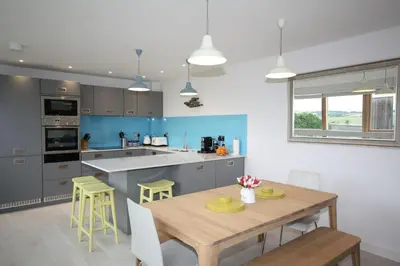 a kitchen with a wooden table and yellow chairs at House 18 in Looe