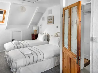 two beds in a room with white walls at Bora House in Newquay