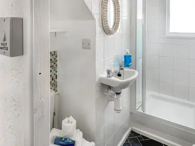 a white bathroom with a sink and a shower at Bora House in Newquay
