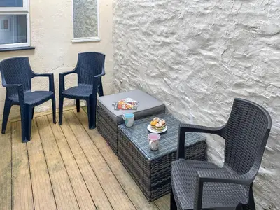a patio with three chairs and a table with a plate of food at Bora House in Newquay