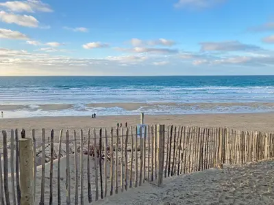 a wooden fence on a beach with the ocean at Bora House in Newquay