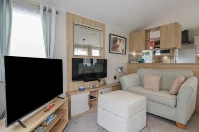 a living room with a flat screen tv and a chair at The Maples, no 56 in St Austell