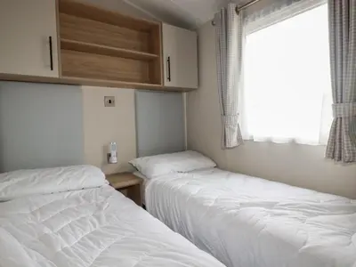 two beds in a small room with a window at The Maples, no 56 in St Austell