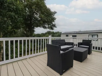 a deck with two chairs and a table on it at The Maples, no 56 in St Austell