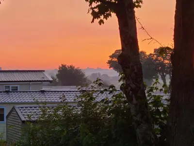 a sunset view of a house and trees at The Maples, no 56 in St Austell