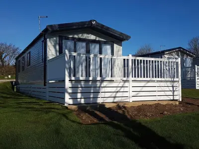 a small house with a white fence in the grass at The Maples, no 56 in St Austell