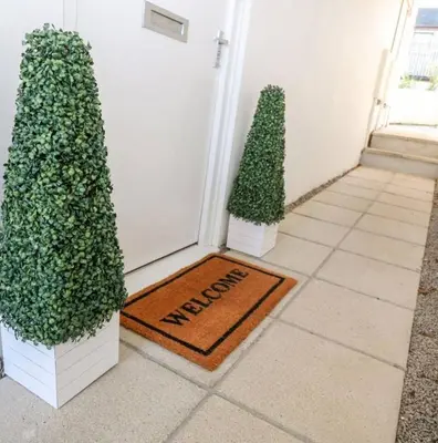 two trees and a welcome mat in front of a door at Falmouth Retreat - Family stays in Falmouth