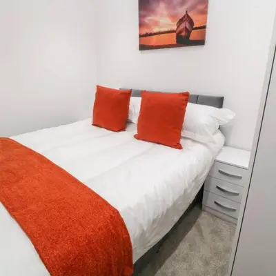a white bed with two orange pillows on it at Falmouth Retreat - Family stays in Falmouth