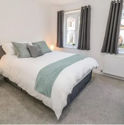 a bedroom with a large white bed and two windows at Falmouth Retreat - Family stays in Falmouth