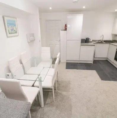 a white living room with white chairs and a glass table at Falmouth Retreat - Family stays in Falmouth