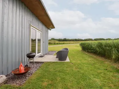 a barn with a table and chairs next to a field at The Tinystore in Bodmin