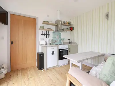 a living room with a table and a kitchen at The Tinystore in Bodmin