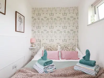 a small bedroom with a bed with green and pink blankets at The Tinystore in Bodmin