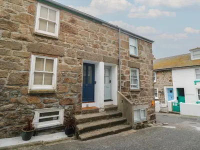 a stone house with a blue door and stairs at Rockpools, 23 Carncrows Street in St Ives