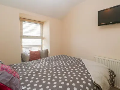 a bedroom with a bed and a flat screen tv at Rockpools, 23 Carncrows Street in St Ives