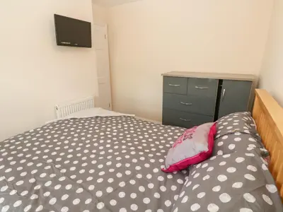 a bedroom with a bed and a dresser and a television at Rockpools, 23 Carncrows Street in St Ives