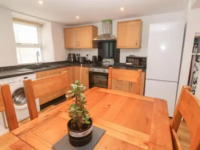 a kitchen with a wooden table with a potted plant at Rockpools, 23 Carncrows Street in St Ives