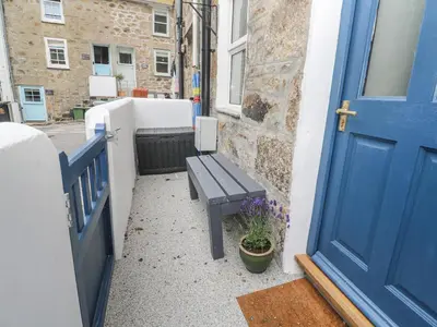 a blue door with a bench next to a building at Rockpools, 23 Carncrows Street in St Ives