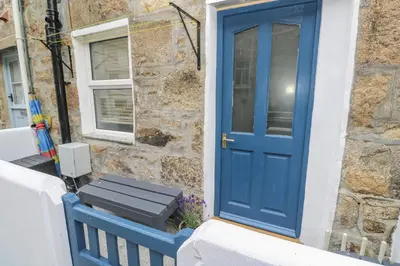 a blue door with a bench in front of a building at Rockpools, 23 Carncrows Street in St Ives