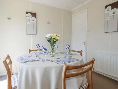 a white table with a vase of flowers on it at Lazy Days in Padstow