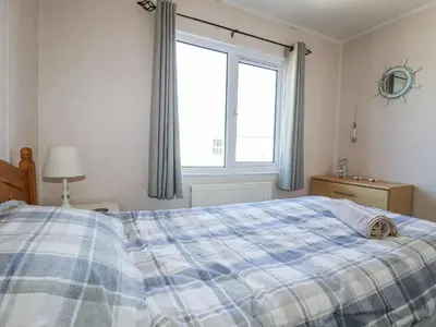 a bedroom with a bed and a large window at Lazy Days in Padstow