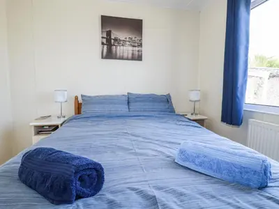 a large bed with blue sheets in a bedroom at Lazy Days in Padstow