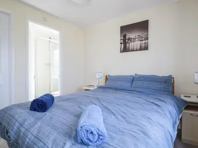 a bedroom with a large bed with blue sheets at Lazy Days in Padstow