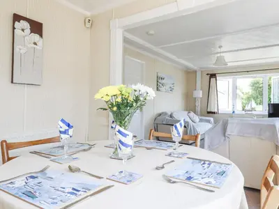 a white table with a vase of flowers on it at Lazy Days in Padstow