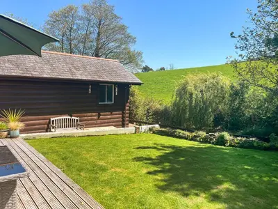 a log cabin with a bench in a yard at Maple Leaf Cottage in Padstow