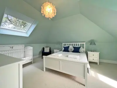 a white bedroom with two beds and a chandelier at Trenare in Truro