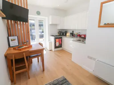 a kitchen with white cabinets and a wooden table at Carn Brea in Redruth