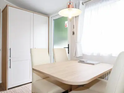 a dining room with a wooden table and white chairs at Meadow 46 in Newquay